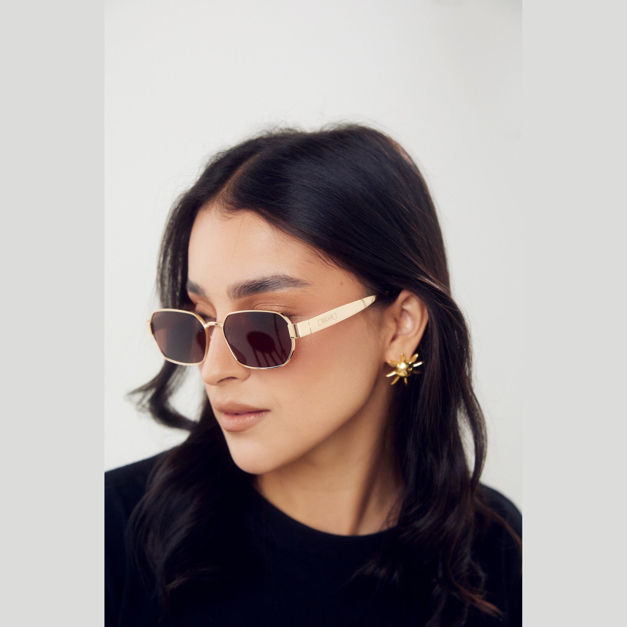 Modelo usando los lentes de sol CHIC de Solivo en un entorno al aire libre, mostrando su estilo contemporáneo y protección UV400.