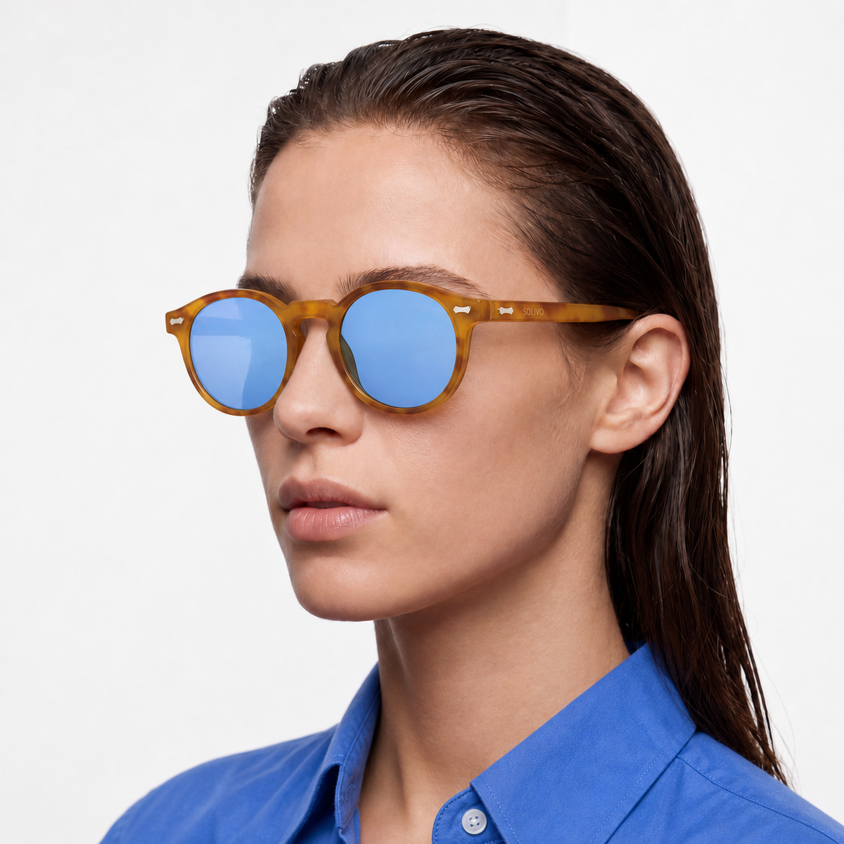 Modelo femenina con lentes Solivo SIA Carey Celeste, montura carey con logotipo SOLIVO en la patilla y lentes celestes, vista de tres cuartos.