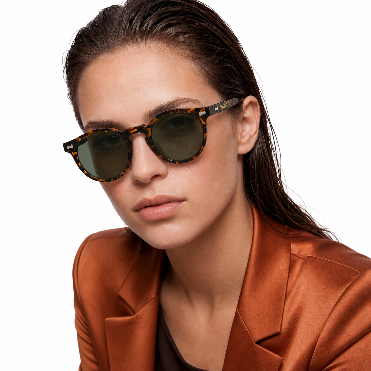 Modelo femenina Solivo con lentes SIA Fuego Olivo, pose editorial inclinada y logotipo SOLIVO visible